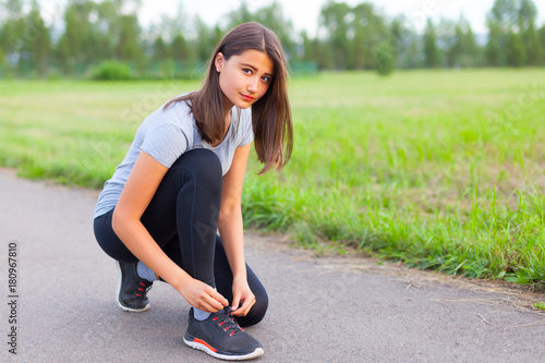 A teenage girl ties her shoelaces, prepares for a run
