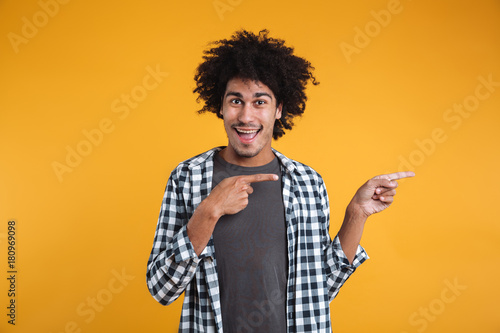 Portrait of a cheerful young african man pointing fingers away