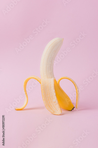 Peeled banana on pink background with copy space