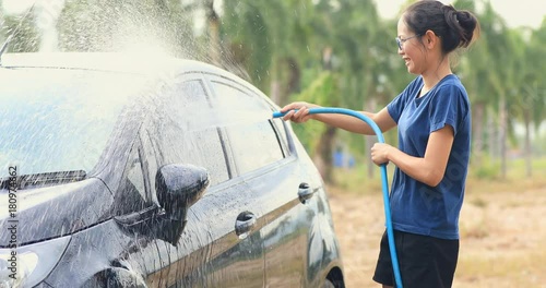 Asian woman is washing car in the garden at home
