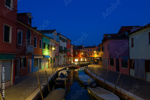 Colorful houses and boats at night in Burano, Venice Italy.