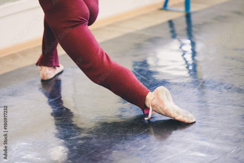 dancing, rehearsal, fitness concept. strong slim legs of ballet dancer  wearing in red sweatpants for rehearsal and satin pointe shoes in the  moment of movement Stock Photo