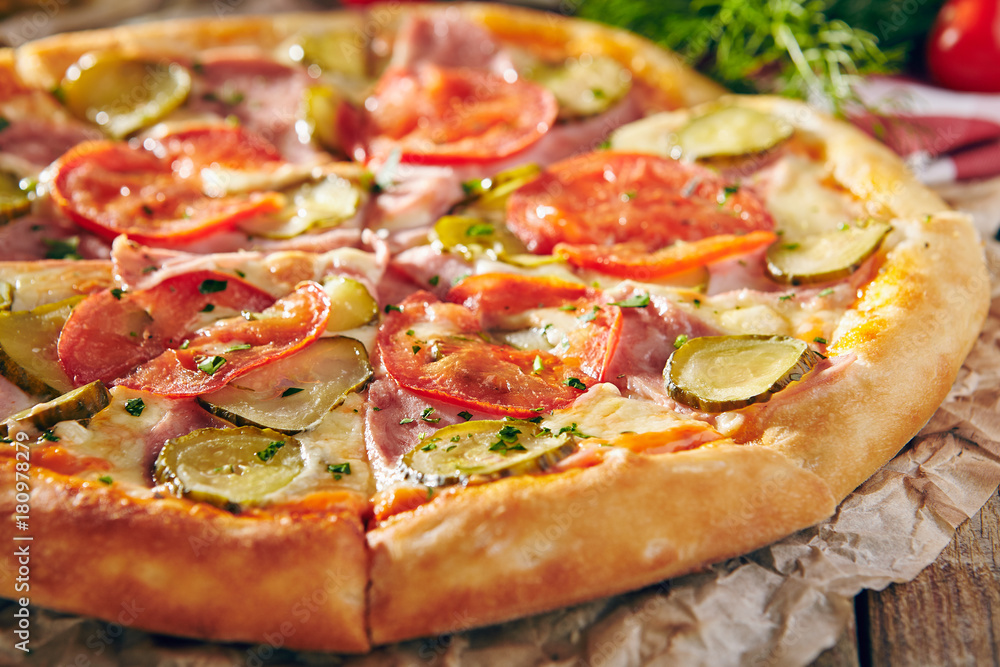 Pizza Restaurant Menu - Delicious Fresh Pizza with Tomato, Ham and Pickled Cucumber. Pizza on Rustic Wooden Table with Ingredients Pizza Restaurant Menu - Delicious Fresh Pizza with Tomato, Ham and Pickled Cucumber. Pizza on Rustic Wooden Table with Ingredients