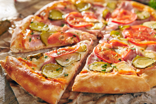Pizza Restaurant Menu - Delicious Fresh Pizza with Tomato, Ham and Pickled Cucumber. Pizza on Rustic Wooden Table with Ingredients