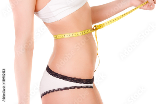 young woman with slim figure measuring a belly size with a measuring tape