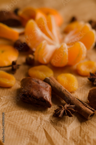 christmas concept - mandarin without the skin, spices, skin of an orange, stars of anise, cinnamone, dried fruit on the parchment on the table