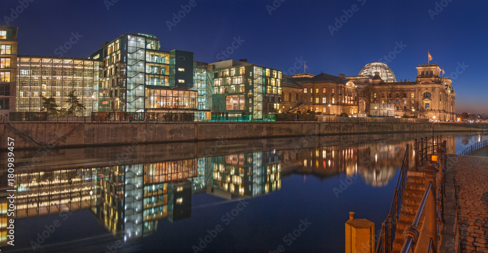 Berlin - Panorama of modern buildings on the riverside and Reichstag over the Spree river in evening dusk.