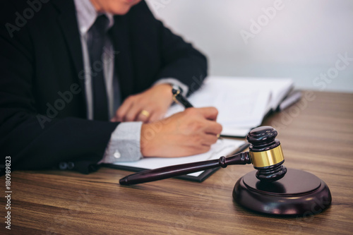 Gavel on wooden table and Lawyer or Judge working with agreement in Courtroom theme, Justice and Law concept