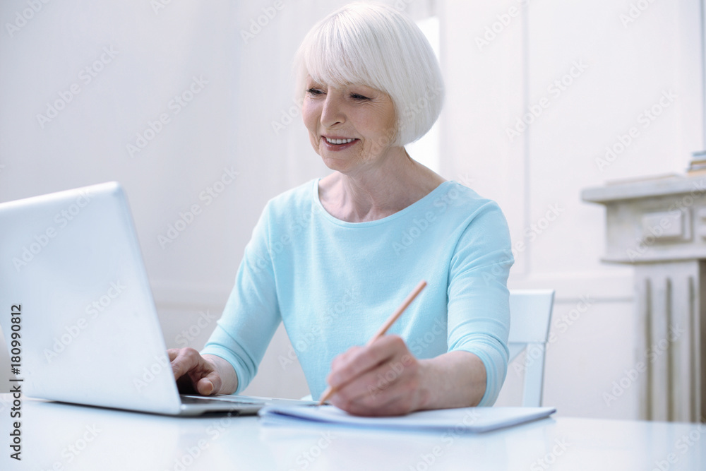 Progressive pensioner. Active progressive cheerful old woman looking happy while working at her laptop Progressive pensioner. Active progressive cheerful old woman looking happy while working at her laptop