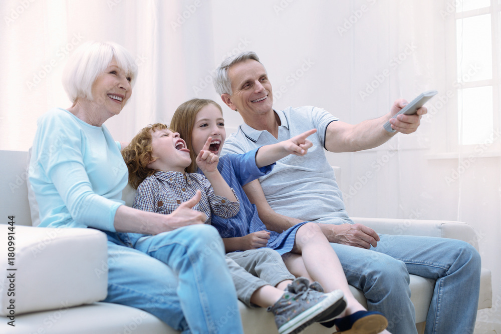 Laughing relatives. Energetic positive cheerful relatives sitting together on a sofa and laughing