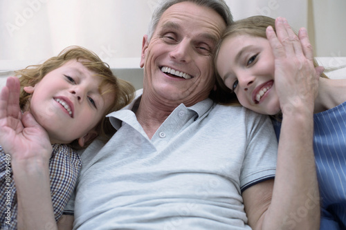 Happy grandfather. Emotional smiling old man looking happy while spending time with his grandchildren