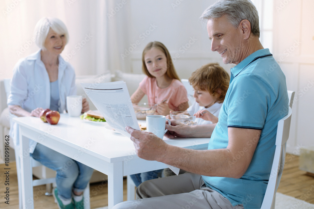 Obraz premium Relaxed morning. Pleasant calm family sitting at the table and eating their tasty breakfast