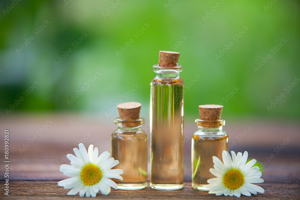 Essence of flowers on table in beautiful glass bottle Essence of flowers on table in beautiful glass bottle