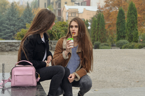 Two girlfriends try to warm up with a hot drink in the outdoors