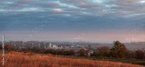 Panoramic rural landscape with fog lit by the rising sun.