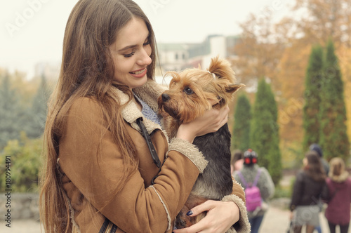 Girl holds a small dog in her arms, hugs and kisses her