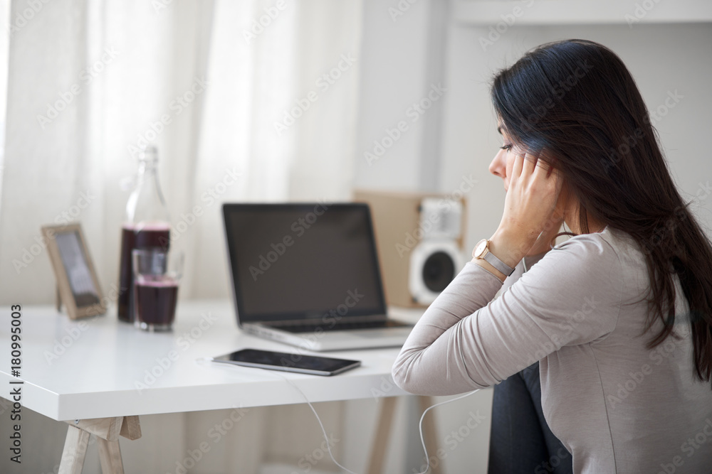 Woman sitting in home office and using tablet