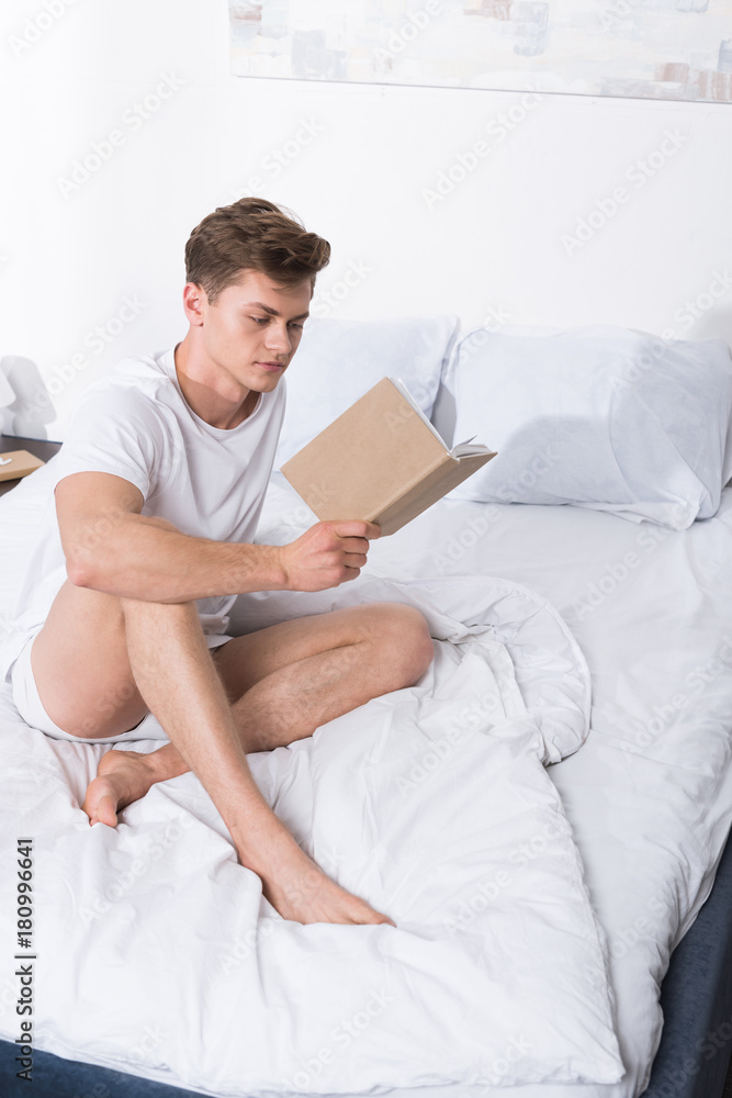 man reading book in bed