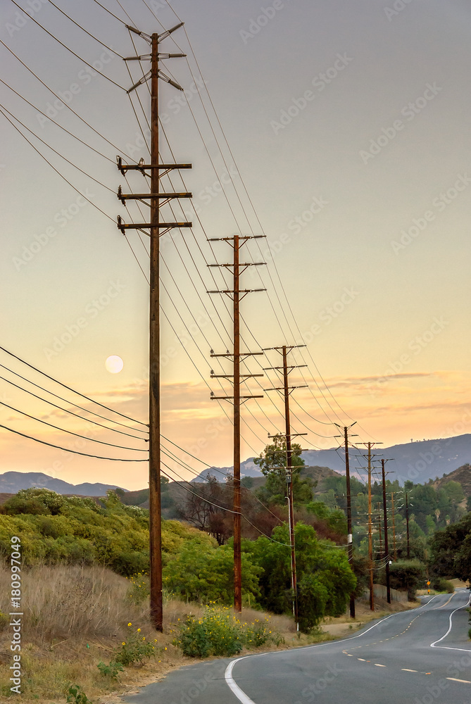 Utility poles and electric cables run parallel to California highway.