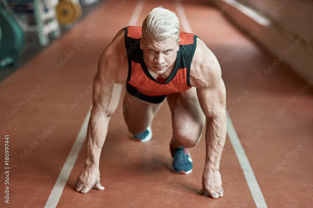 Fototapeta premium Confident male sprinter standing on a start position