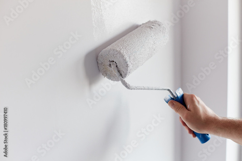 Slika na platnu Male hand painting wall with paint roller