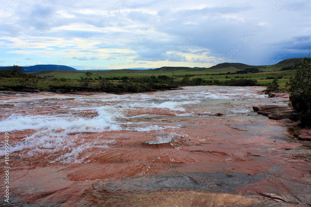 river flowing over red jasper rocks in gran sabana