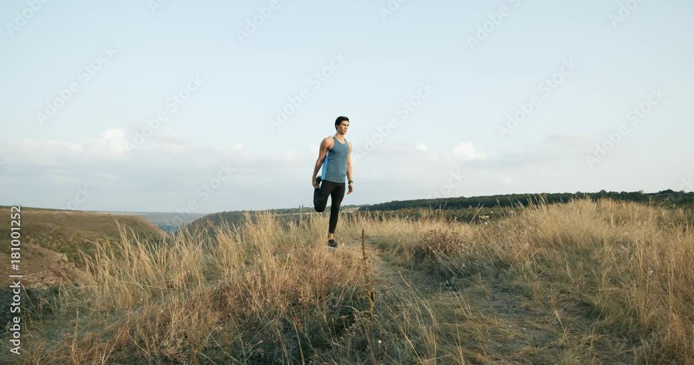 Slow Motion Male athlete exercising outdoors. Sports and active lifestyle. Man running into sunset, colorful sunset sky. Slow Motion Male athlete exercising outdoors. Sports and active lifestyle. Man running into sunset, colorful sunset sky.