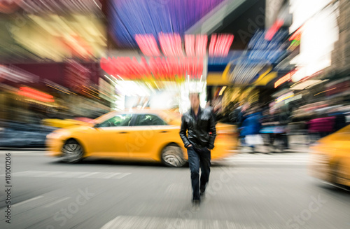 Radial blur of yellow taxicabs and unidentified person walking on 42nd street crossroad in Manhattan downtown district - Everyday commuting life New York City on rush hour in urban business area