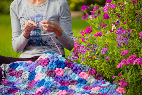 The girl knits on a green glade and in flowers
