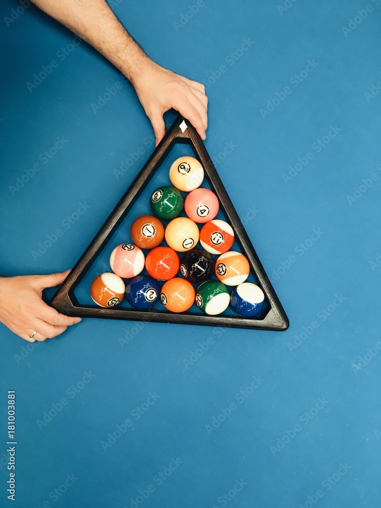Puramid of pool billiard balls in hands on blue table - obrazy, fototapety, plakaty 