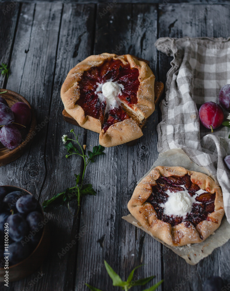 plum crostata pies with ice cream on gray wooden table with textile, fresh plums and herbs plum crostata pies with ice cream on gray wooden table with textile, fresh plums and herbs