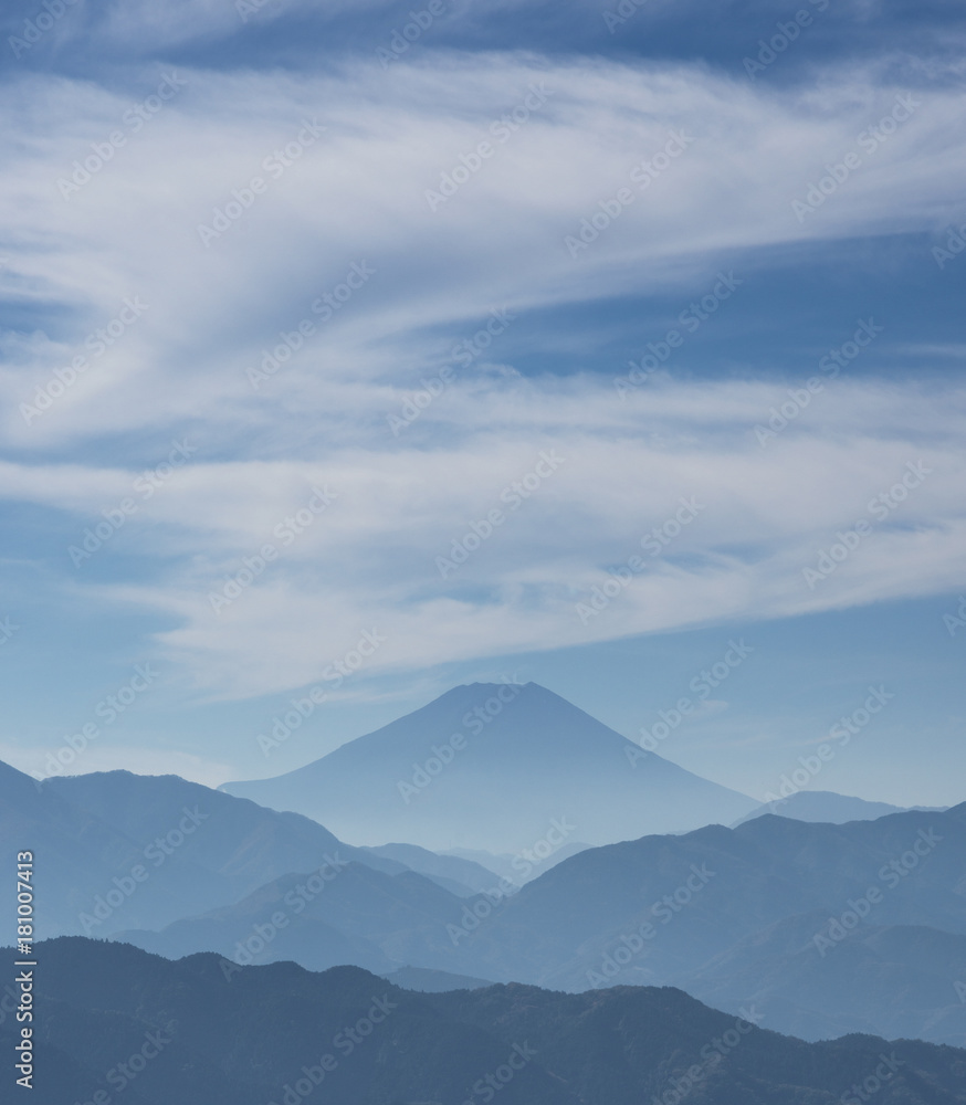 Iconic Mount Fuji wrapped in misty clouds like and old painting, seen from Mount Takao in Japan