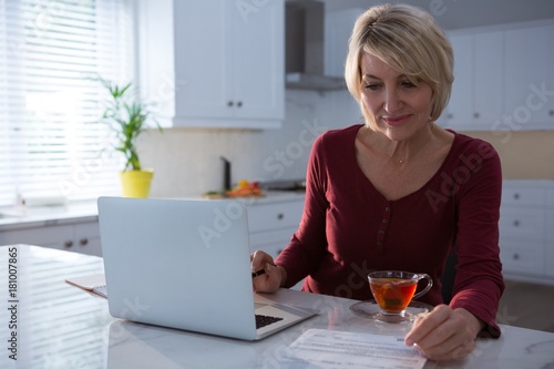 Woman looking at bill in kitchen