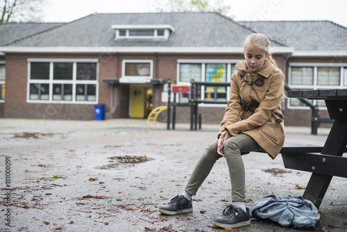 Foto sad lonely girl sitting on bench at schoolyard