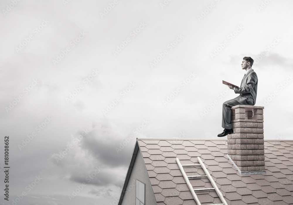 Student guy in suit on brick house roof reading book Student guy in suit on brick house roof reading book