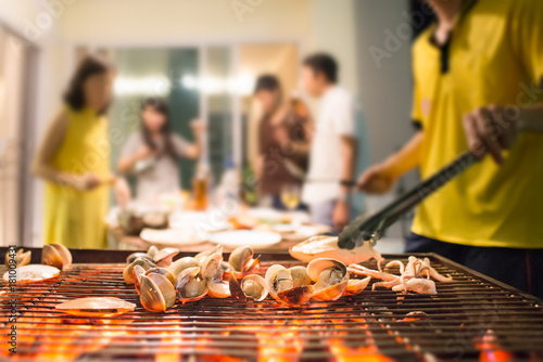 Selective focus on roasted seafood party with blurred background of people
