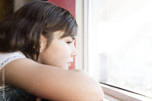 nice little girl by the window feel sad photo