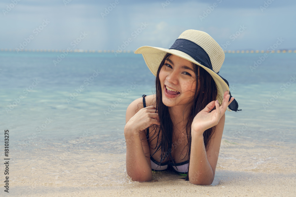 Beautiful woman wearing a hat lying on the beach
