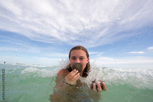 Portrait of young woman in water, holding shells © Image Source
