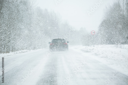 The car is driving on a winter road in a blizzard photo