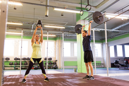 man and woman with weights exercising in gym