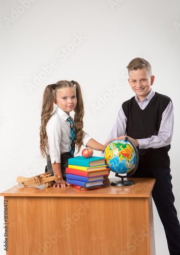 Happy boy and girl sit at a school desk, isolated on white background. Ideal for banners, registration forms, presentation, landings, presenting concept.