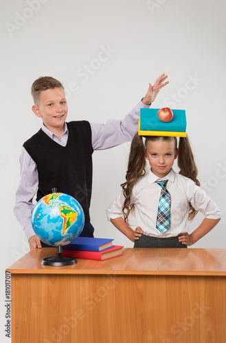 Happy boy and girl standing at a school desk, isolated on white background. Ideal for banners, registration forms, presentation, landings, presenting concept.