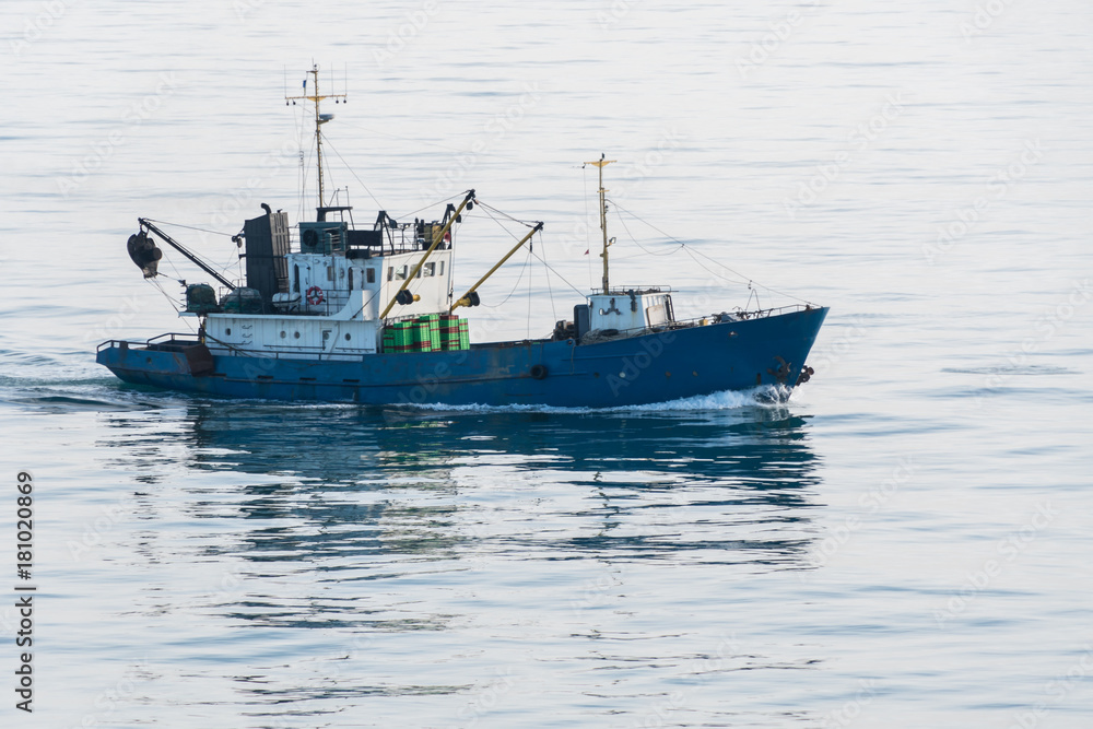 Silhouette of engaged fishing craft surrounded by seagulls, in Kerch strait, Russia.