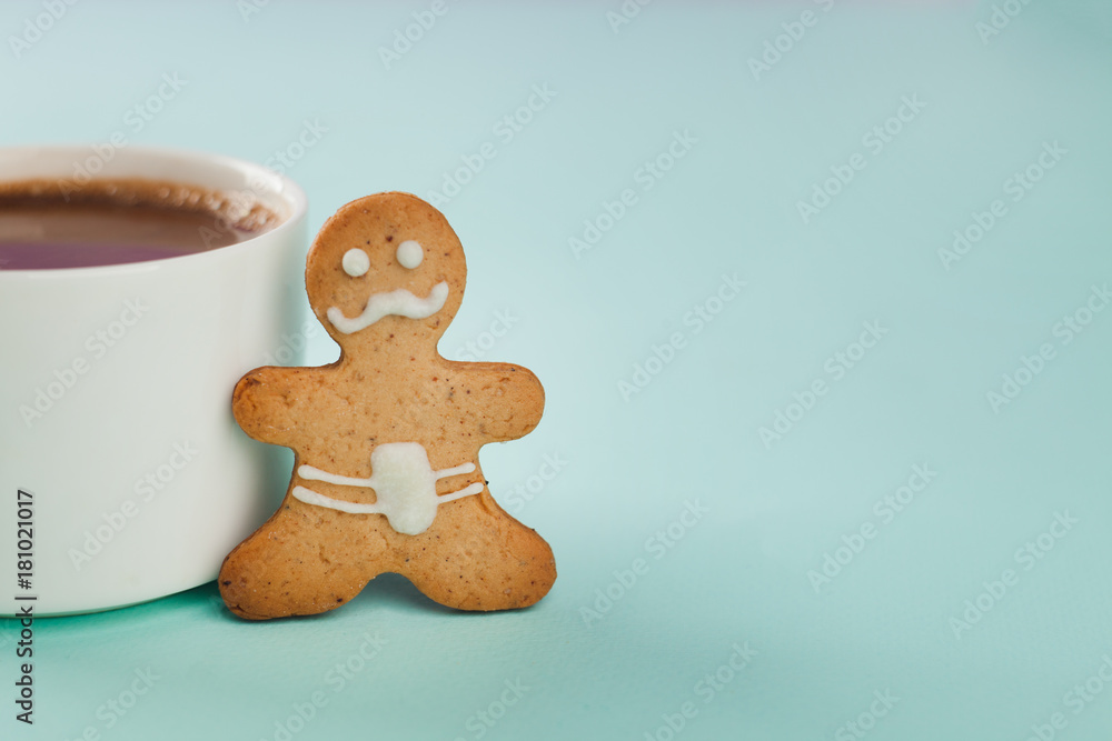 whiskered gingerbread man stands near a white mug, copy space whiskered gingerbread man stands near a white mug, copy space
