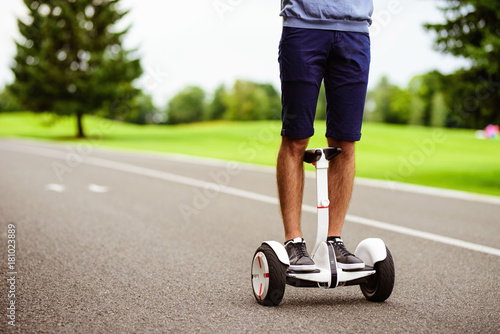 Close up. A man is driving through the park on a gyroboard.
