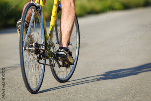 Detail of cyclist man feet riding bike on road.
