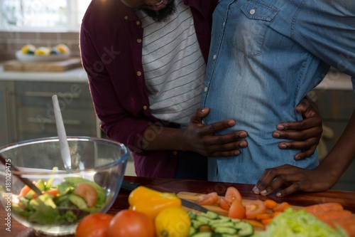 Man touching womans pregnant belly in the kitchen photo