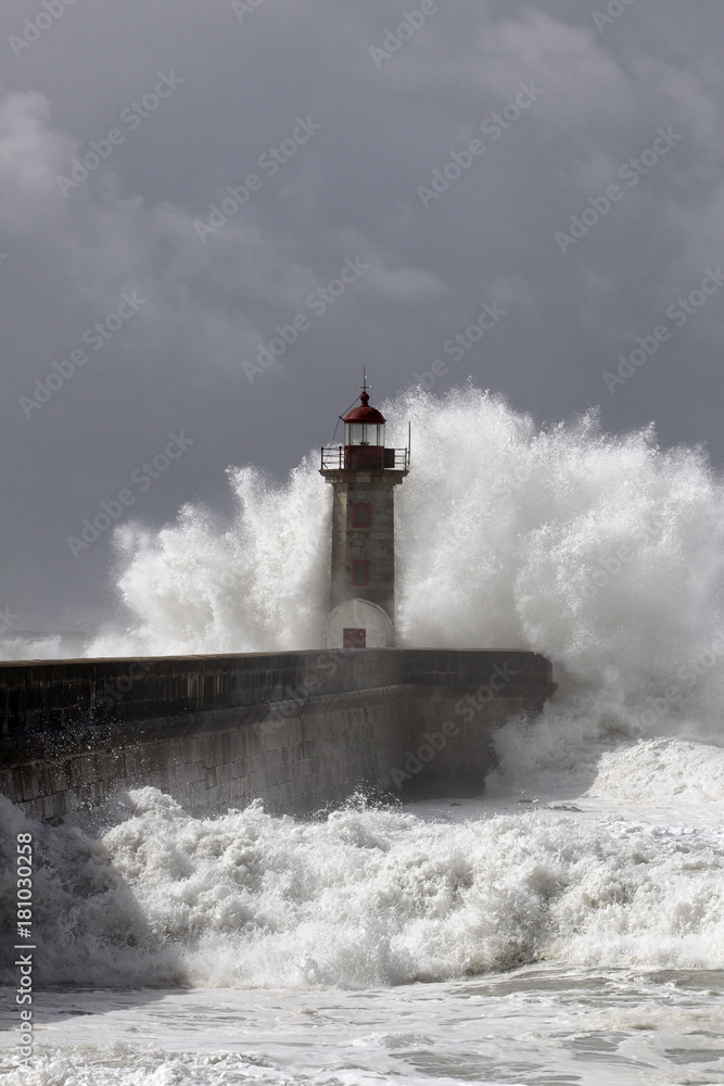 Stormy wave against pier and lighthouse