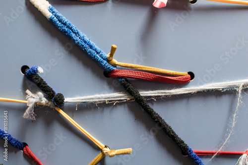 Colored elastic cotton strips interlaced on a metal panel as decoration. Woven threads with different finishes. Rope in a panle photo